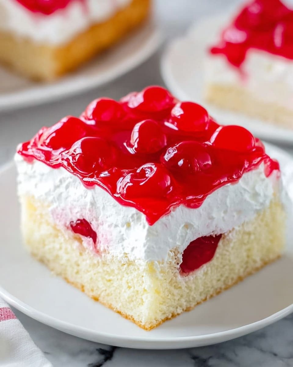 A square piece of cake is shown on a white plate placed on a white marbled surface. The cake has three layers: the bottom layer is light yellow and looks soft and spongy, the middle layer is thick white whipped cream spreading evenly, and the top layer is a shiny red cherry topping with whole cherries and a gel-like texture. Another slice of the same cake is blurry in the background. The photo taken with an iphone --ar 4:5 --v 7