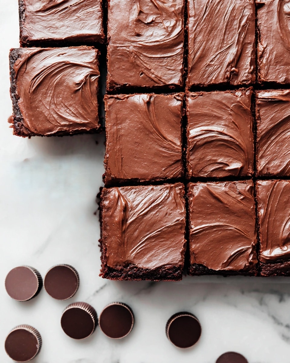 A close-up view of a square chocolate brownies batch cut into twelve squares, with one square slightly pulled away at the bottom left corner. Each brownie has a thick, smooth layer of glossy chocolate frosting with soft swirling textures in dark brown color. The brownies are rich and moist, showing a dense chocolate cake base under the frosting. Below the brownies on a white marbled surface, there are three round, dark chocolate discs scattered nearby. photo taken with an iphone --ar 4:5 --v 7