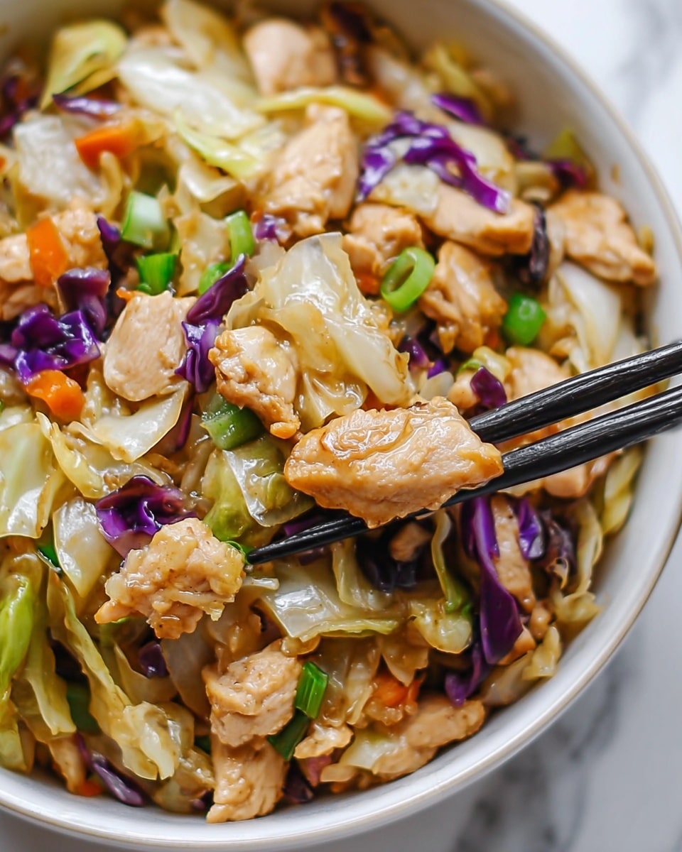 The image shows a close-up of a white bowl filled with a stir-fry dish. The dish has small pieces of cooked chicken that are light brown with some grill marks. Mixed in are various chopped vegetables, including light green cabbage leaves with a slightly translucent look, purple onion pieces, small orange carrot bits, and bright green scallions. The texture looks soft and slightly glossy from a sauce. On the right side, a pair of black chopsticks is picking up some of the food. The bowl is placed on a white marbled surface. Photo taken with an iphone --ar 4:5 --v 7