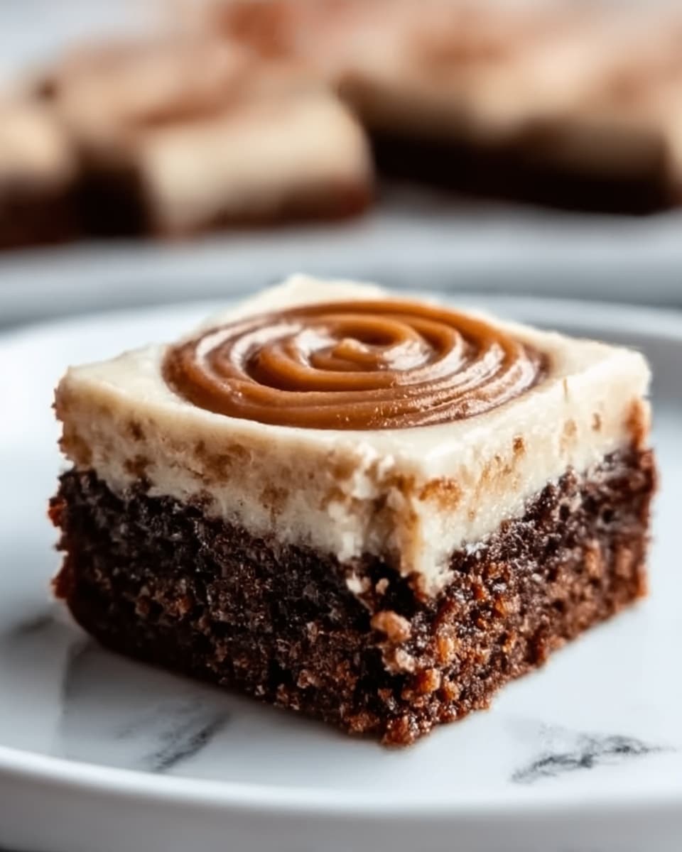 A close-up of a square brownie with three visible layers on a white plate. The bottom layer is dense and dark brown with a slightly crumbly texture. The middle layer is creamy and off-white, smoother and thicker than the bottom. The top layer shows a swirl of light brown frosting or caramel, forming a circular shape right in the center. The background has a white marbled texture. Photo taken with an iphone --ar 4:5 --v 7